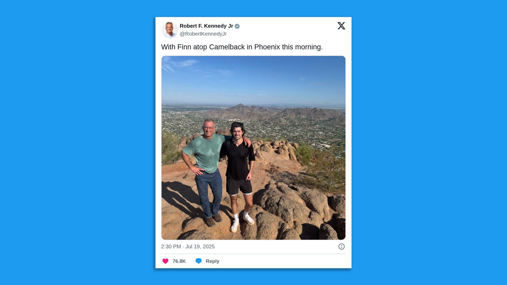 Tweet by Robert F. Kennedy Jr. showing two men posing on rocky terrain atop Camelback Mountain in Phoenix with a cityscape and blue sky in the background.