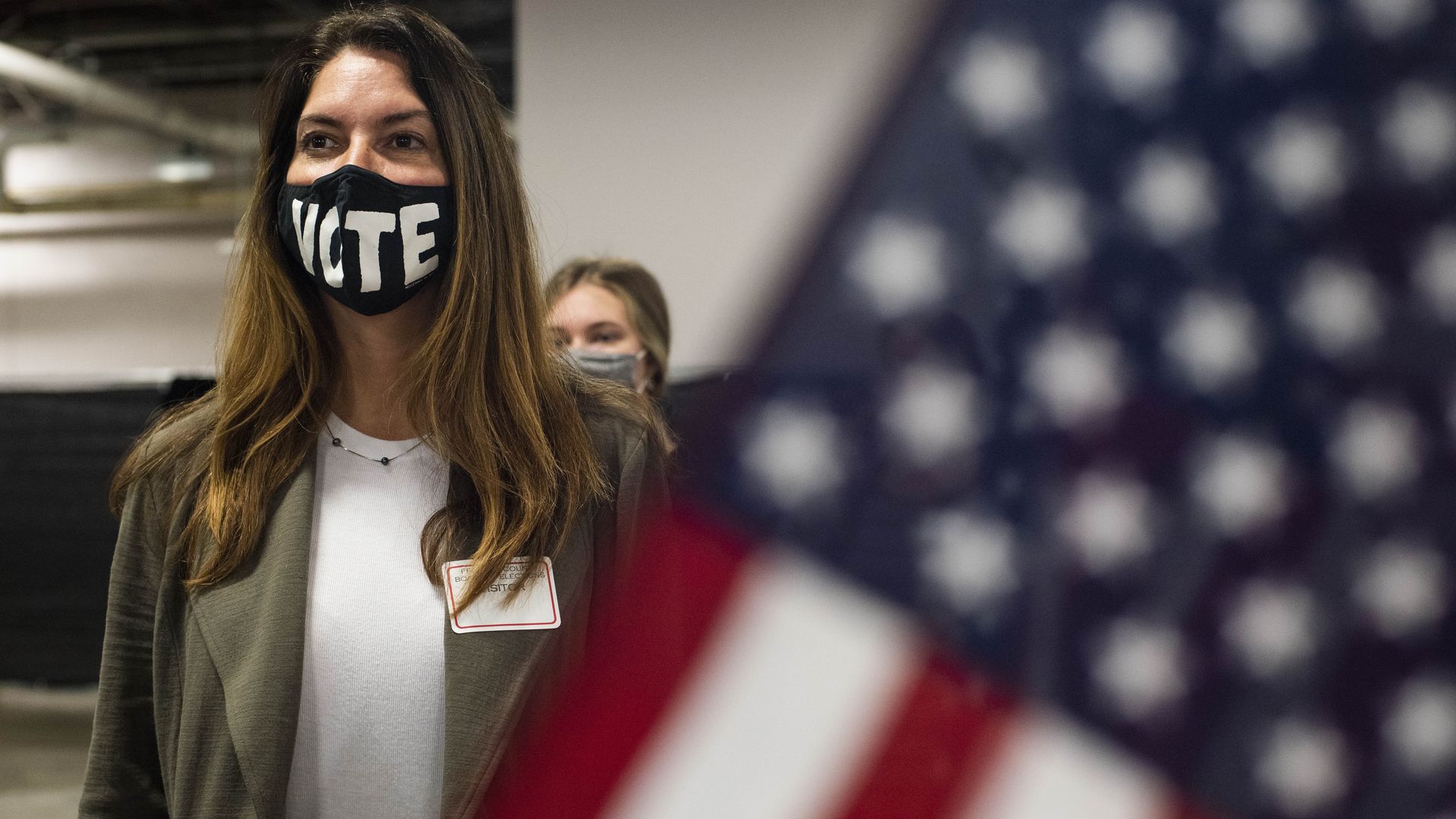 A pollworker wears a mask reading "VOTE" at a voting location.