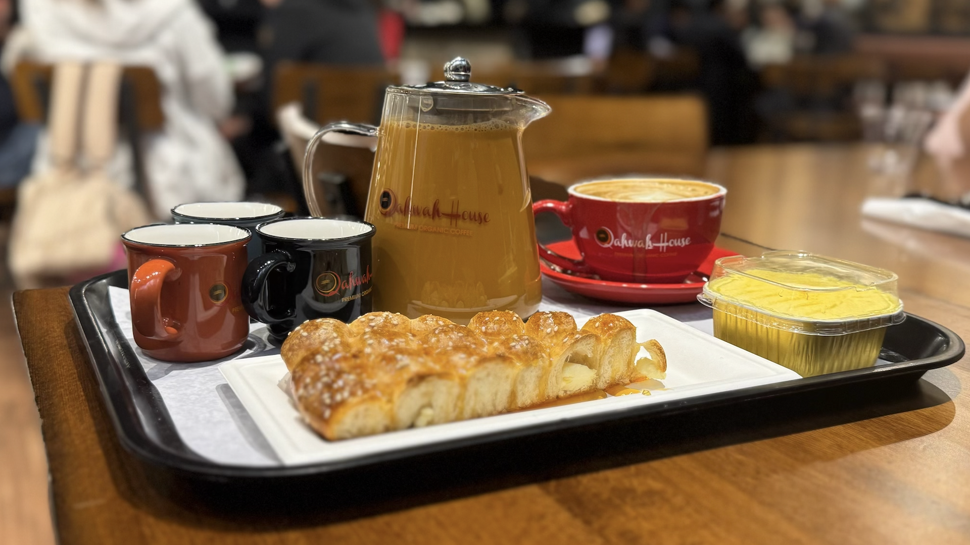 A large pot of chai with a pastry and latte