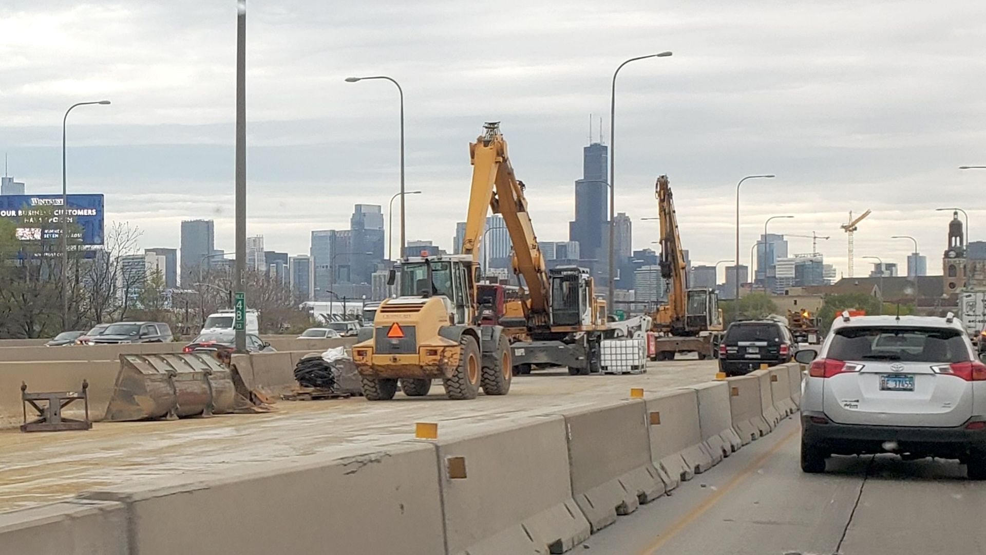 Construction equipment and barriers on the highway with Chicago skyline in background.