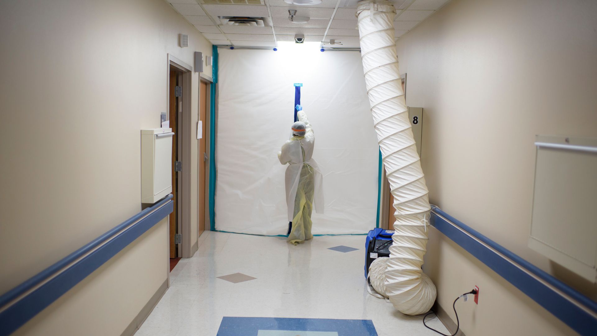 A worker in personal protective gear zips off a COVID-19 unit in a hospital.