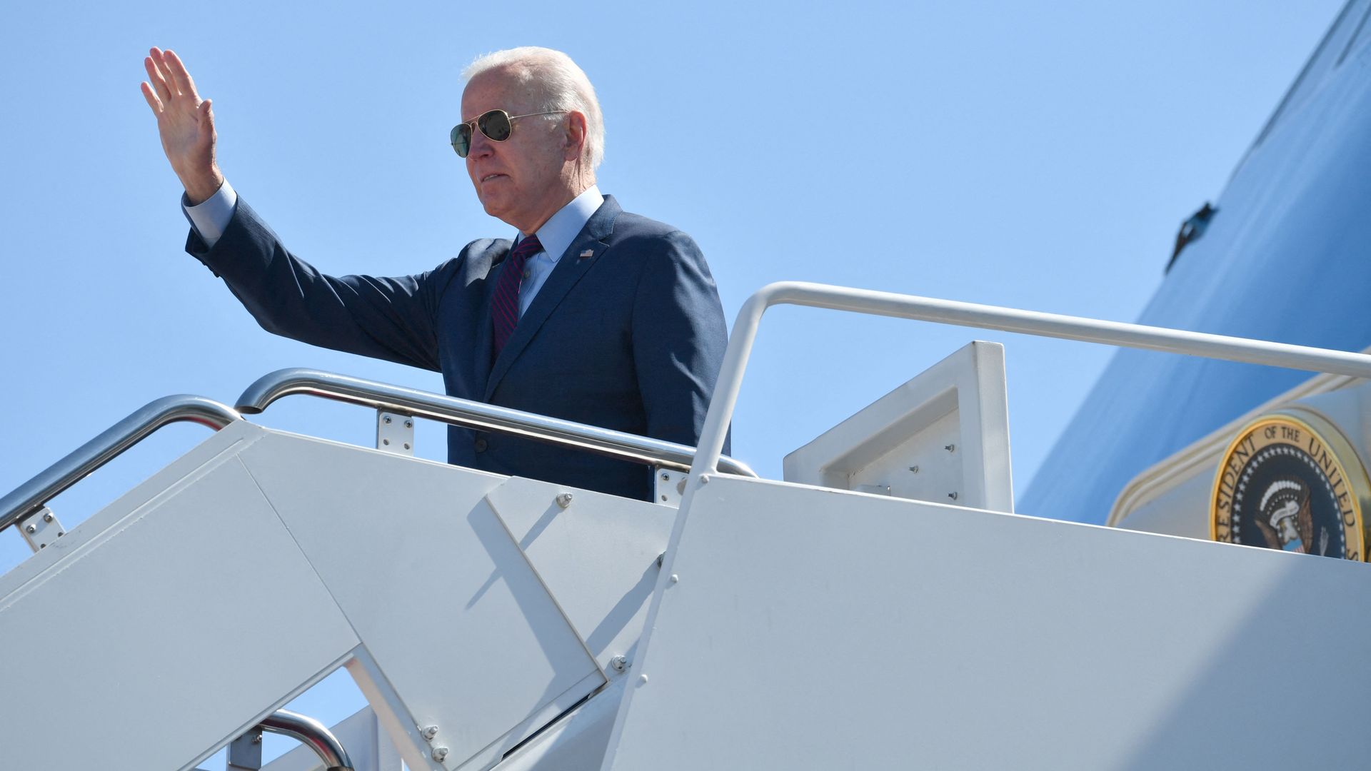 Biden waves while wearing a suit and sunglasses