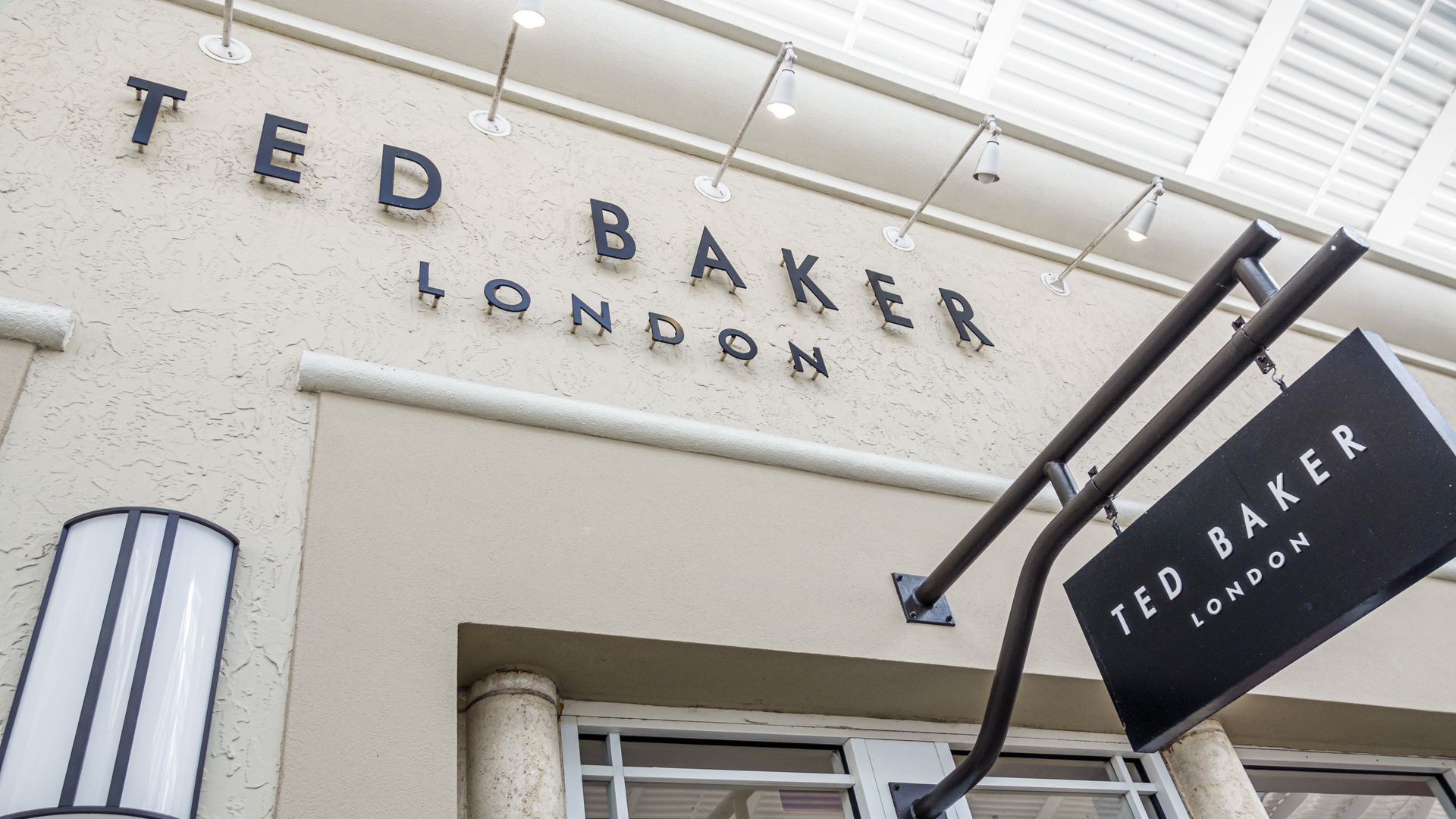 The Ted Baker banner is spelled out above a store entrance in black lettering. 