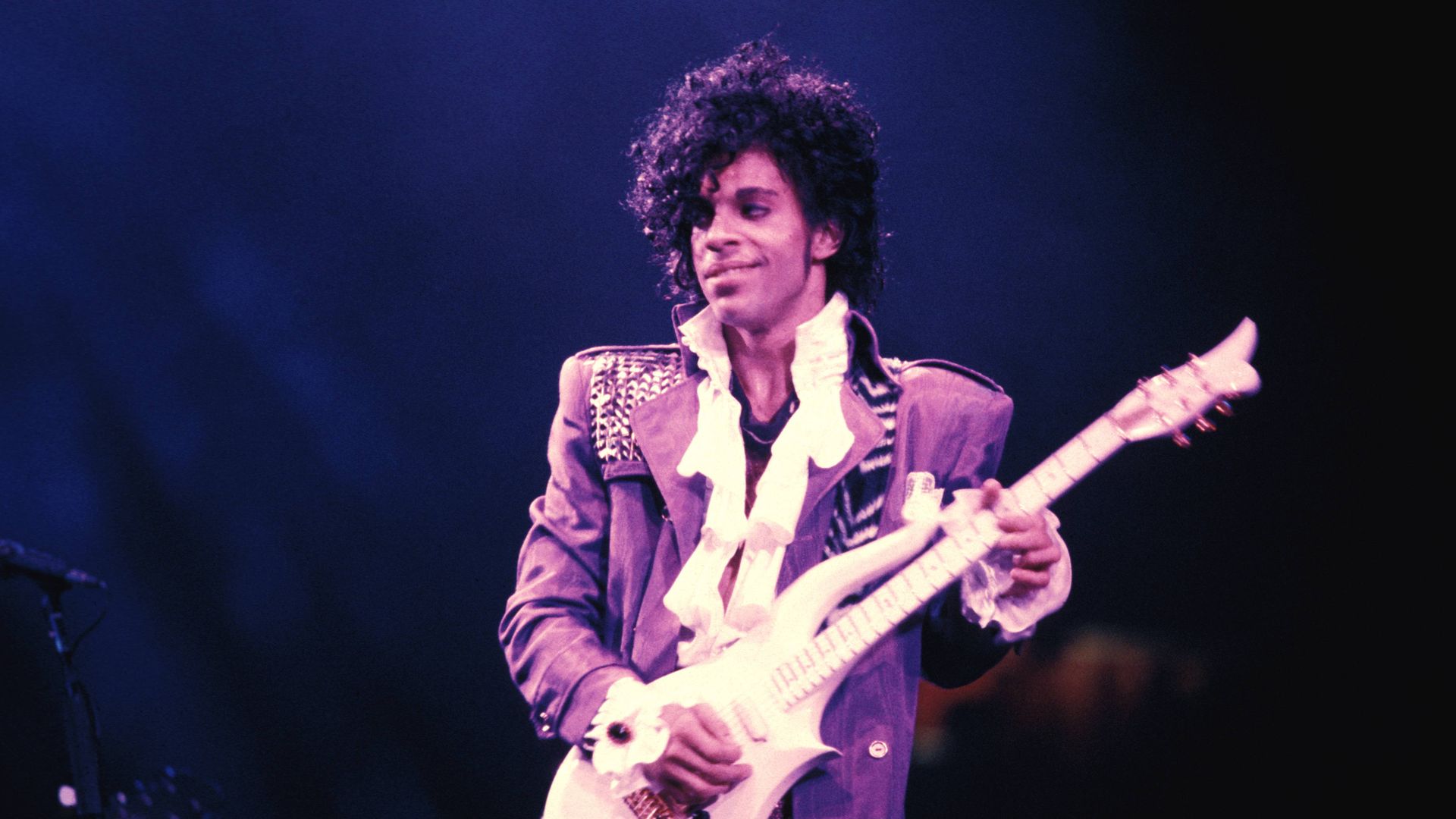 Prince performs on stage in Purple Rain attire circa 1984.