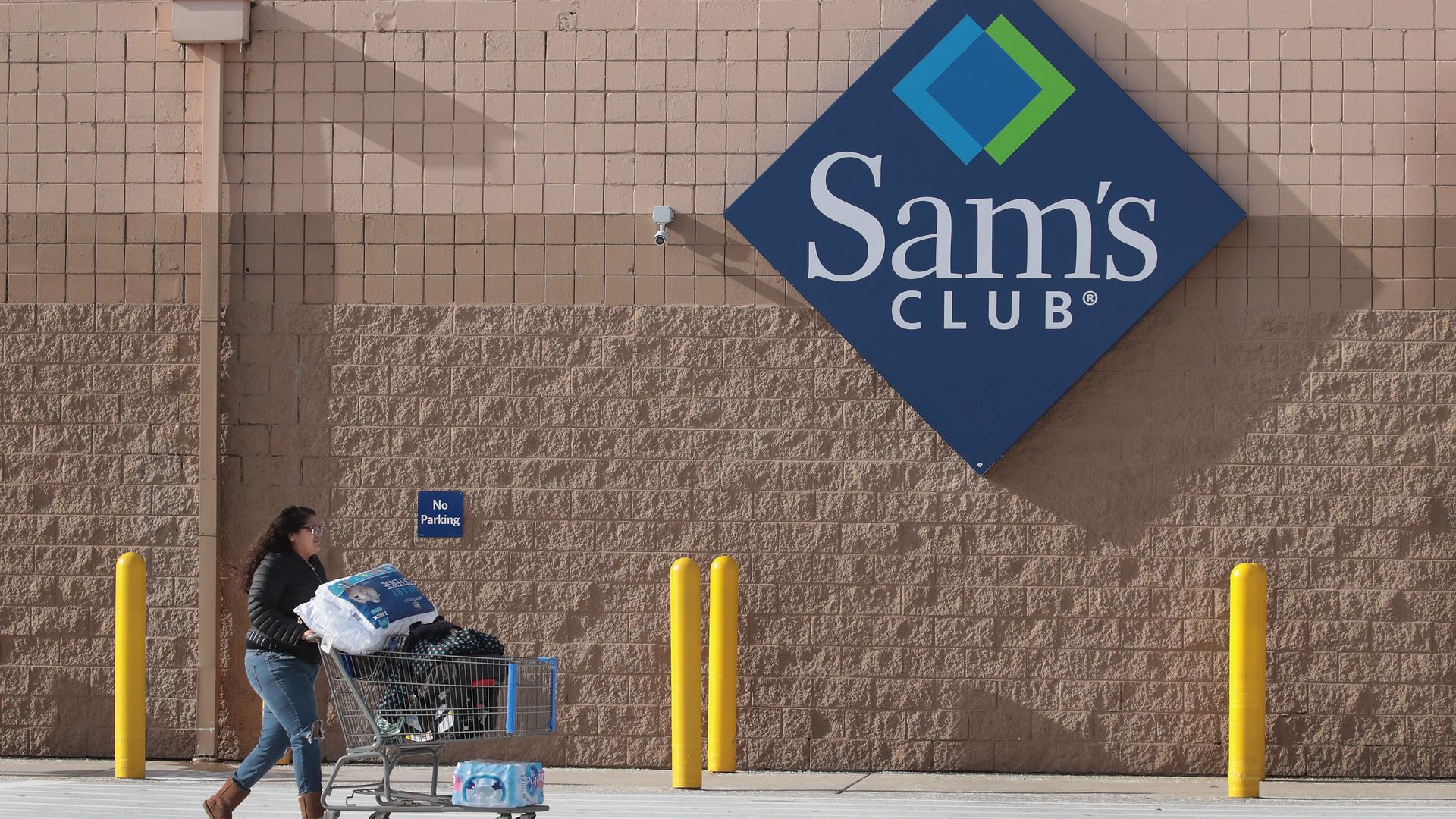 A shopper pushes a cart outside a Sam's Club store