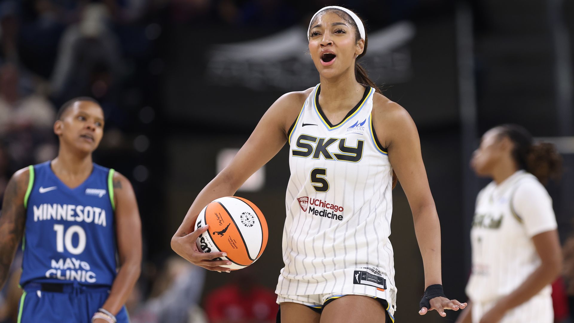 Photo of a woman holding a basketball on a court. 