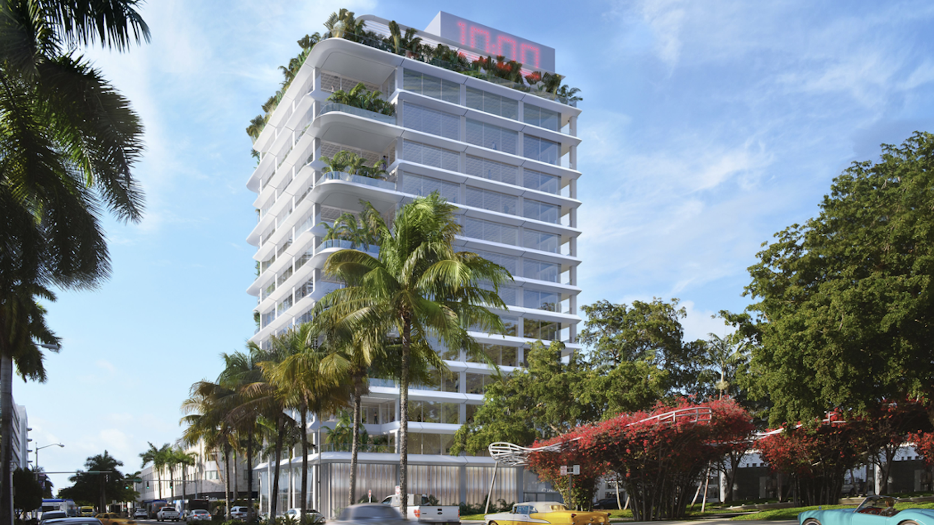 A tall white building with red digital clock at top 