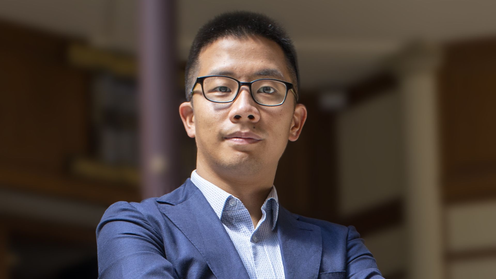 A headshot of Matthew Ahn, wearing glasses a blue shirt and blue suit coat.