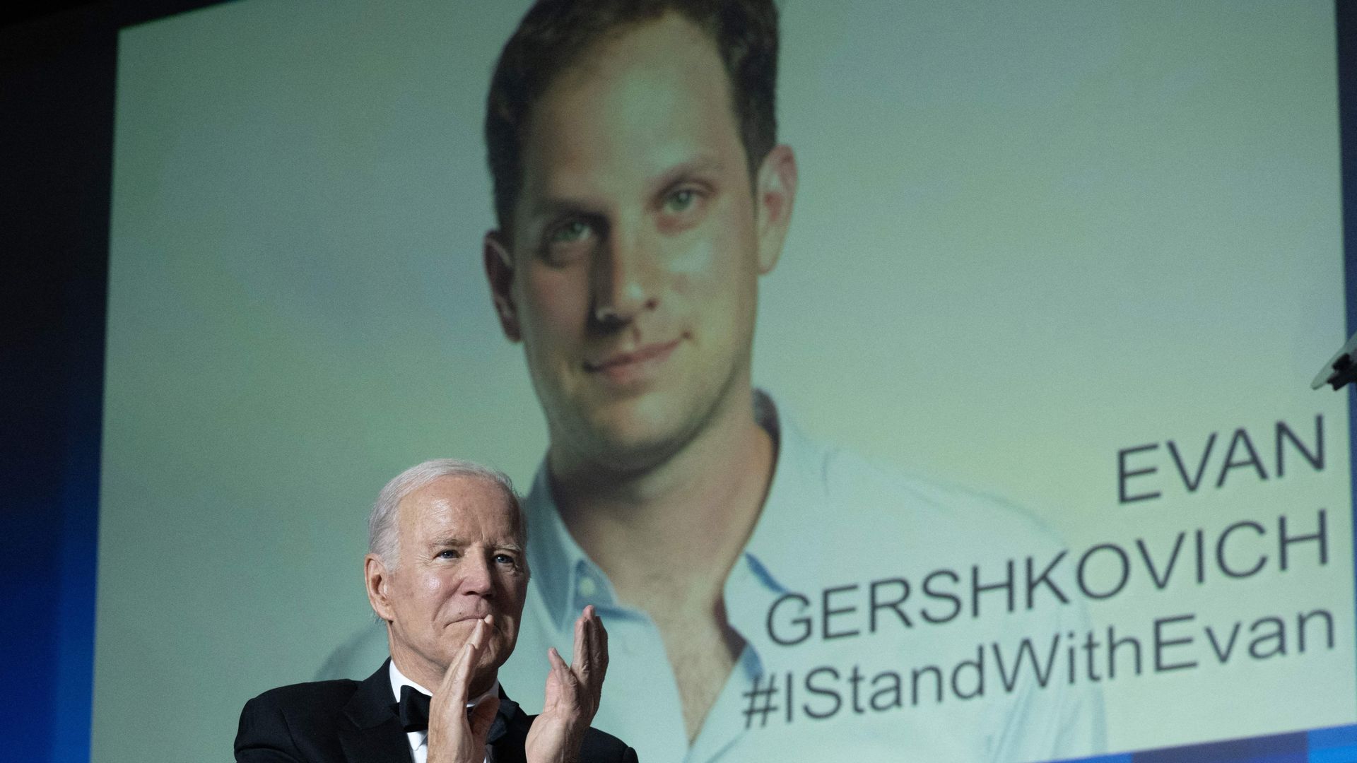 Joe Biden gestures as an image of US journalist Evan Gershkovich appears onscreen during the White House Correspondents' Association dinner