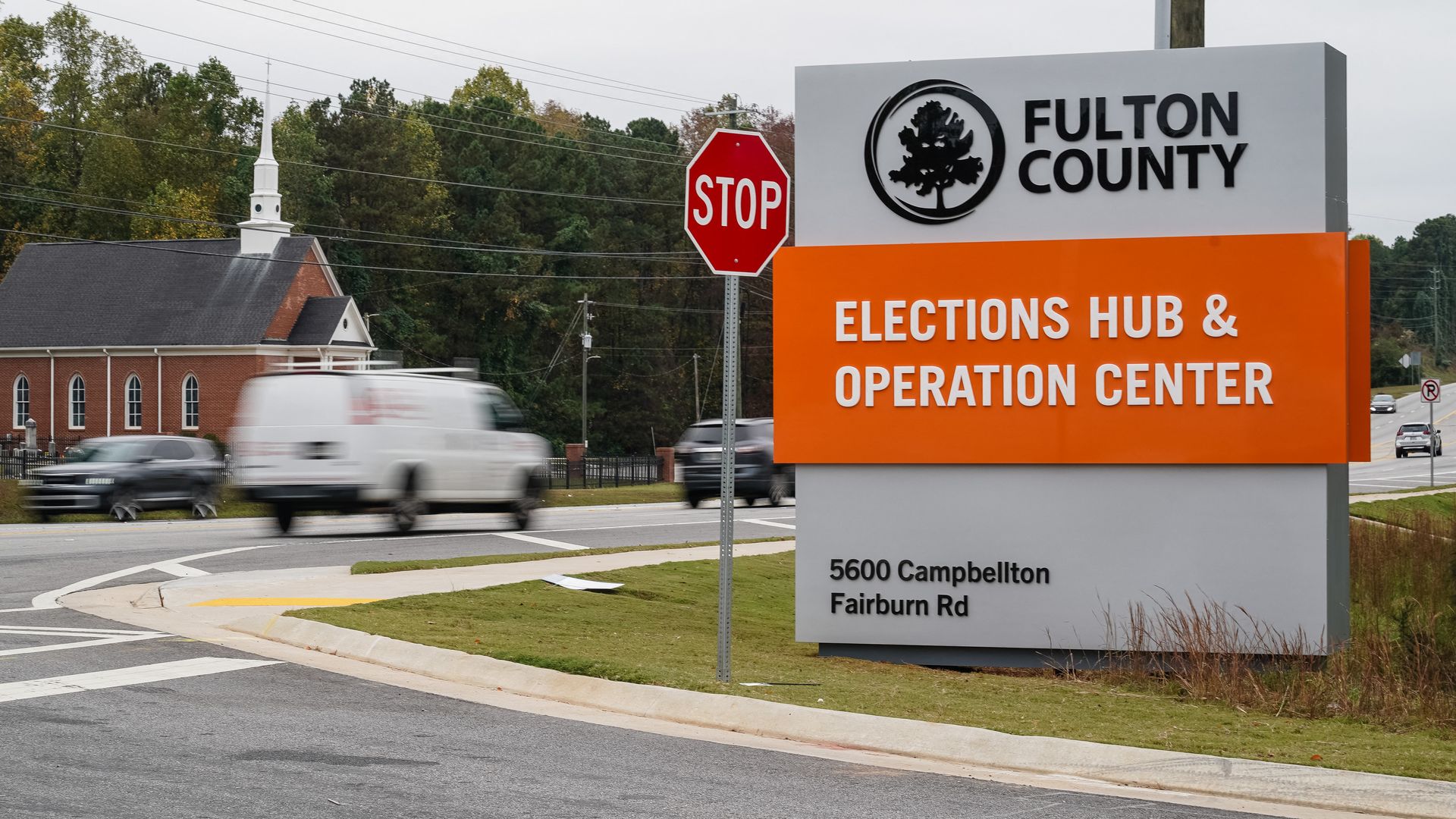 A gray monument sign that has a tree encircled beside the words "Fulton County" and the words "Election Hub & Operations Center" imposed on an orange background. 