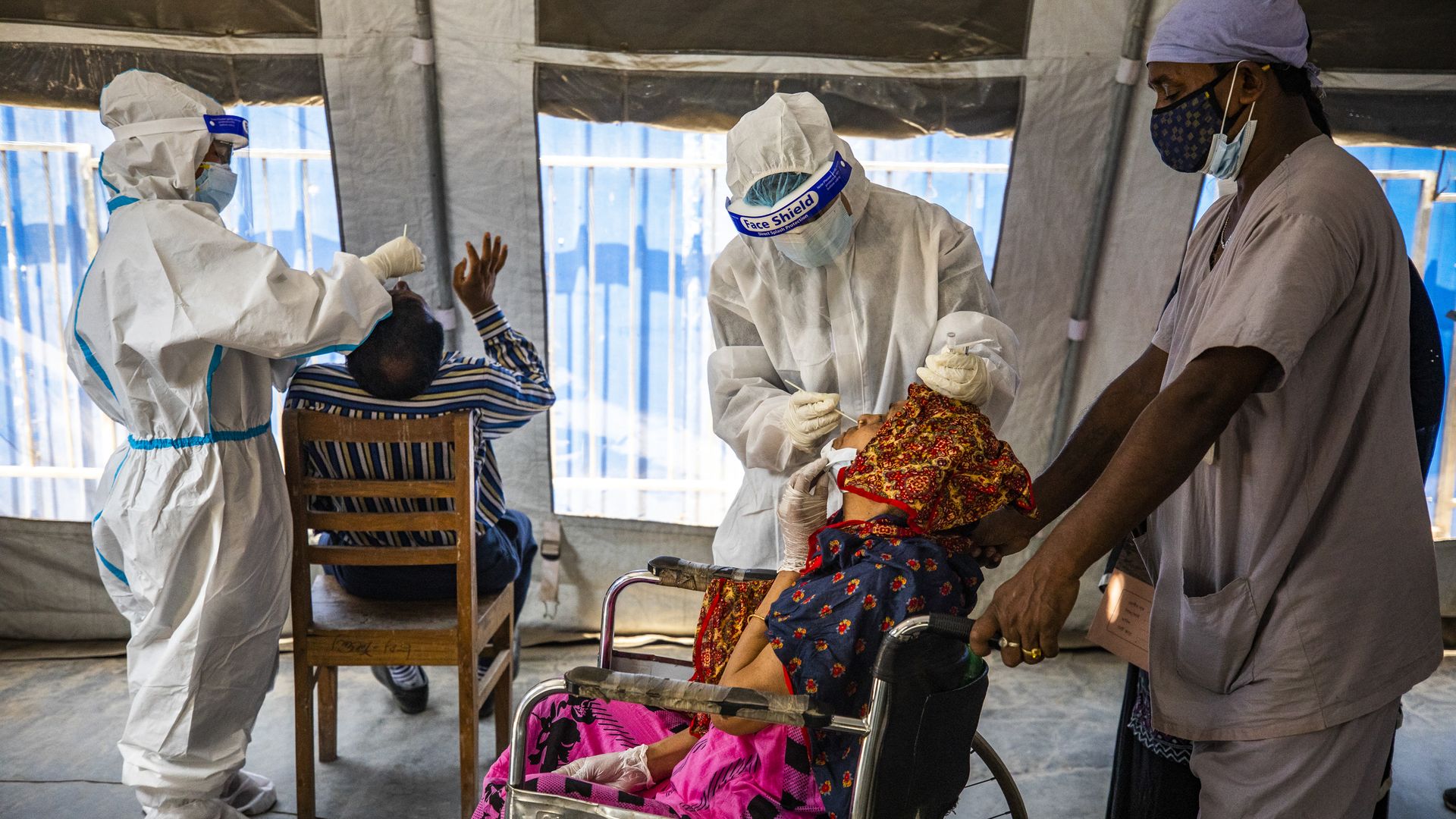 Picture of two Bangladeshi health workers each collecting nasal swabs from people to test for coronavirus