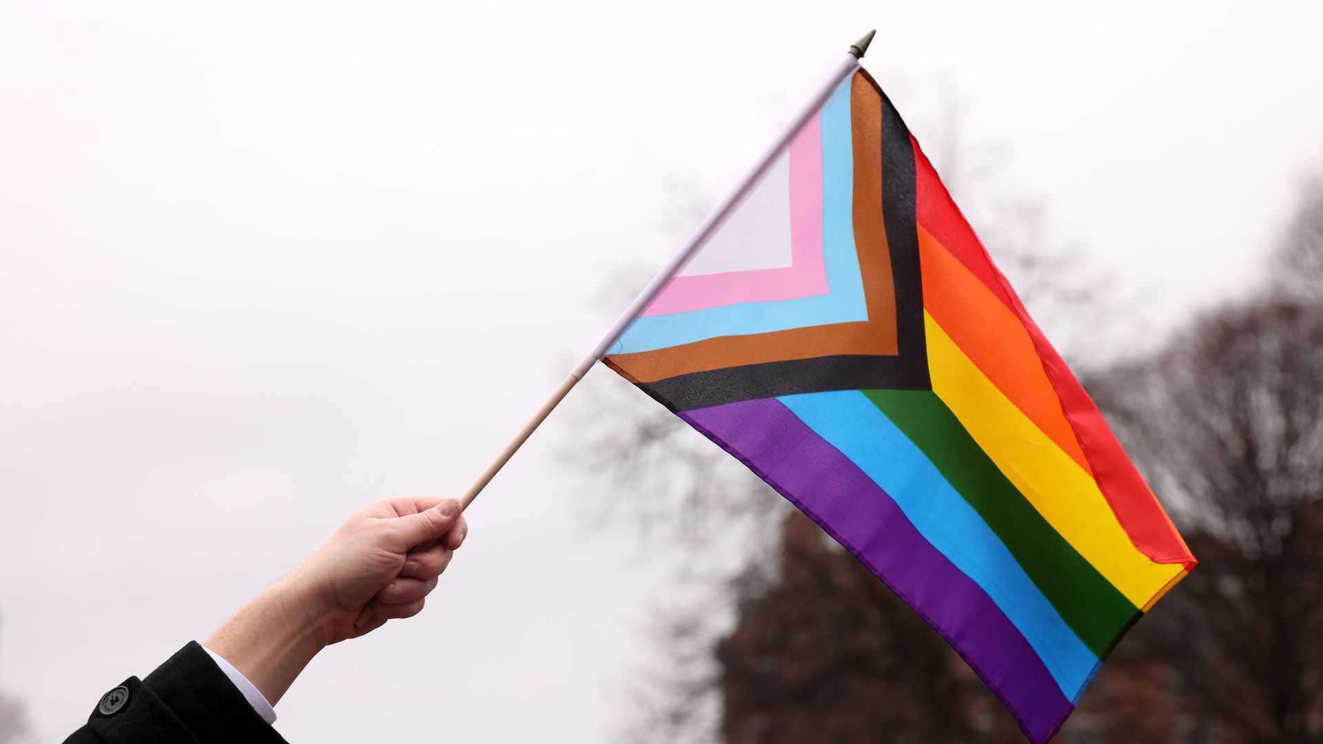 Photo of a hand holding an LGBTQ pride flag in the air