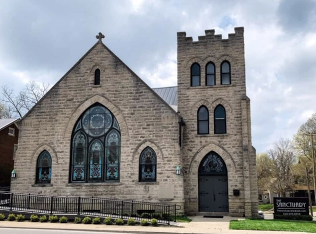 The exterior of a Gothic-style church with stained glass windows.