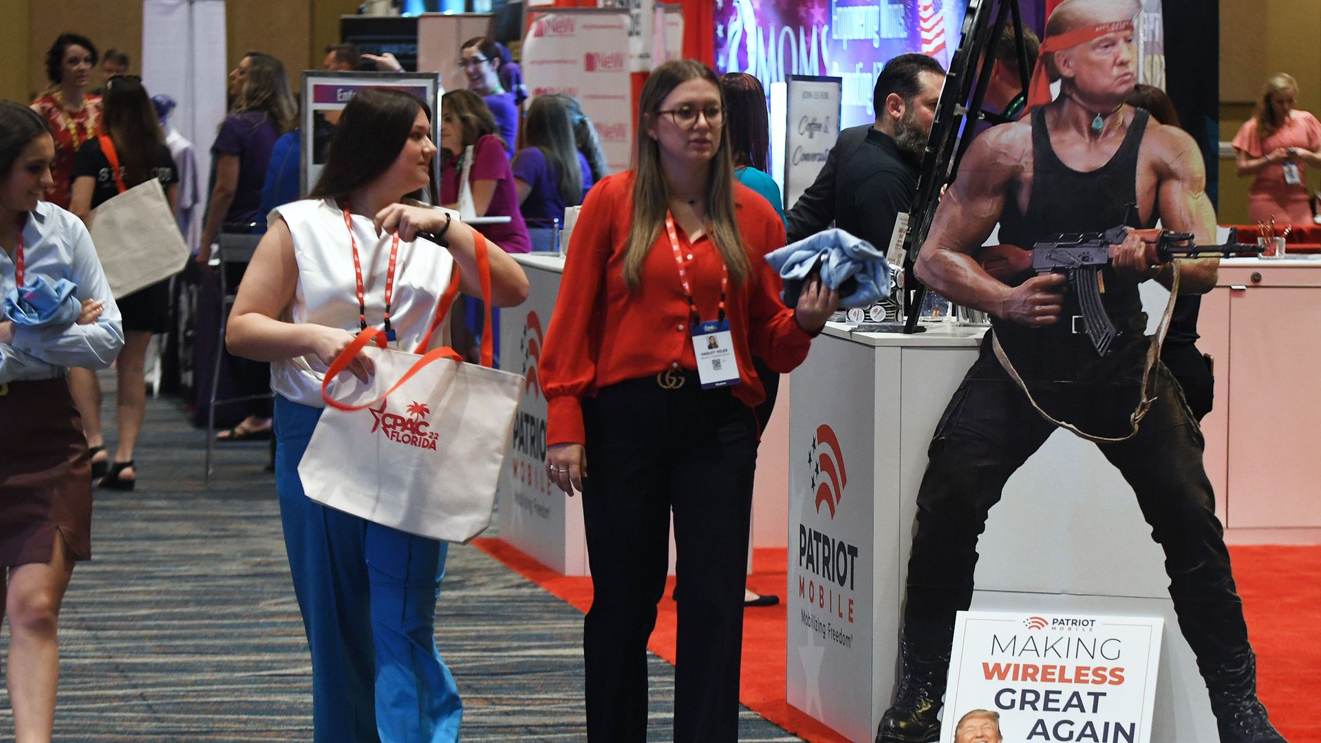 People walking by a display booth featuring Trump's head on Rambo's body