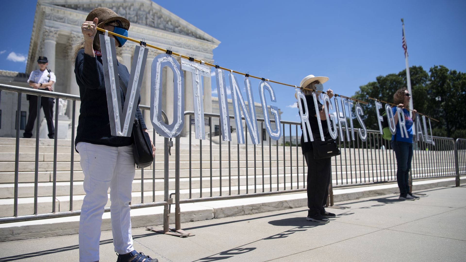 People holding a sign that reads "Voting rights for all" in front of the Supreme Court building in Washington, D.C., in June 2021.