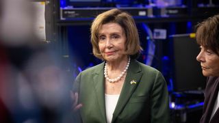 House Speaker Nancy Pelosi in a green suit, white shirt and pearl necklace at the National Accelerator Laboratory in California.