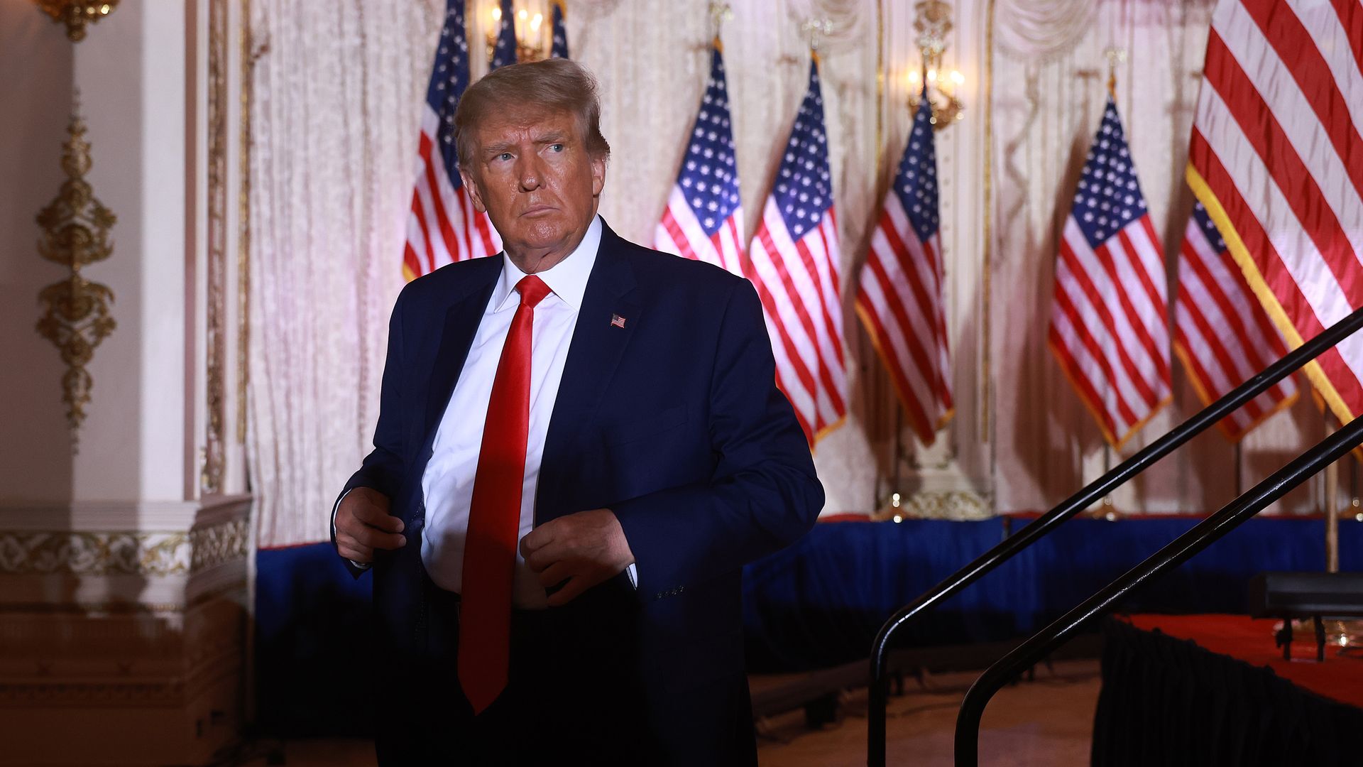 Trump looks at the crowd at Mar-a-Lago, with a shadow over him.