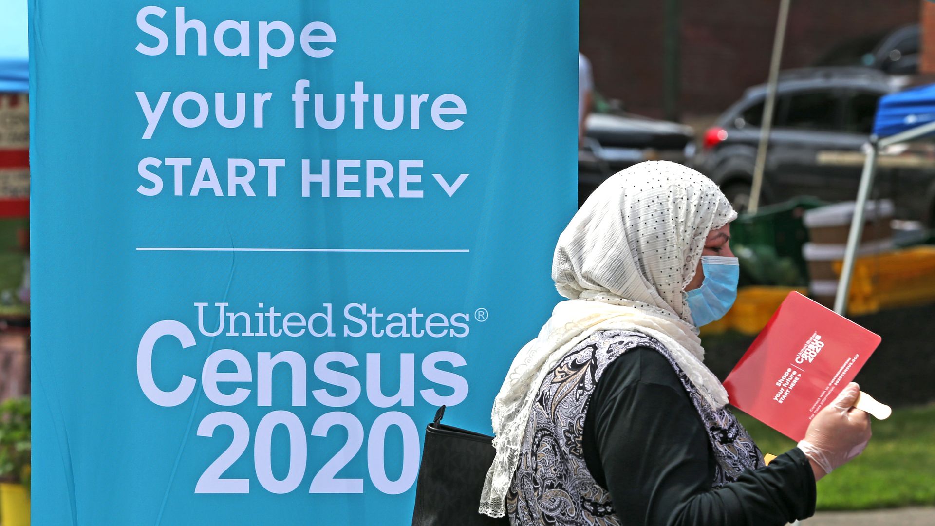  A woman uses a fan to cool off while waiting at a Census 2020 booth at a farmer's market in Everett, MA on July 24