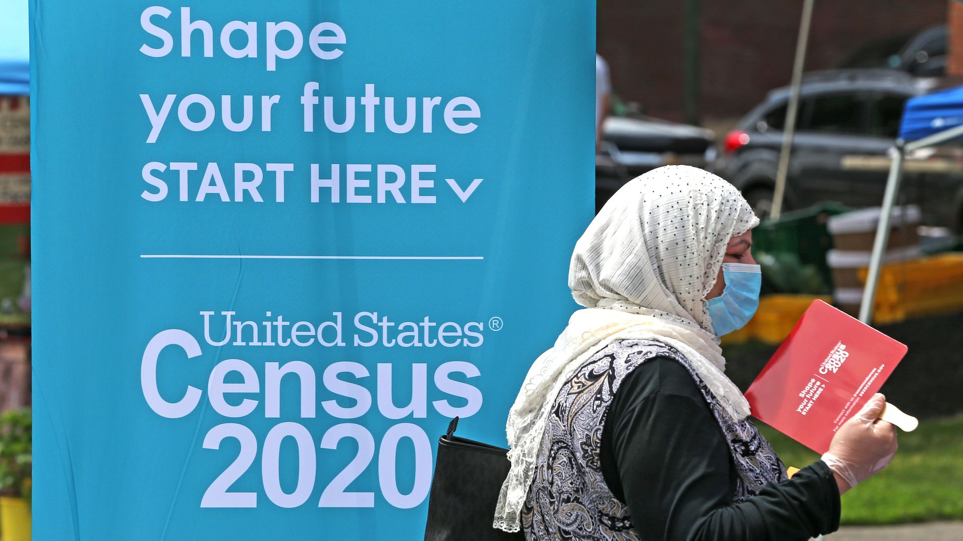 A woman uses a fan to cool off while waiting at a Census 2020 booth at a farmer's market in Everett, MA on July 24