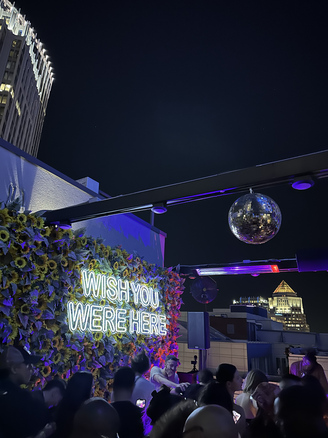 disco ball floats overhead a dance floor with the charlotte skyline in the night sky behind