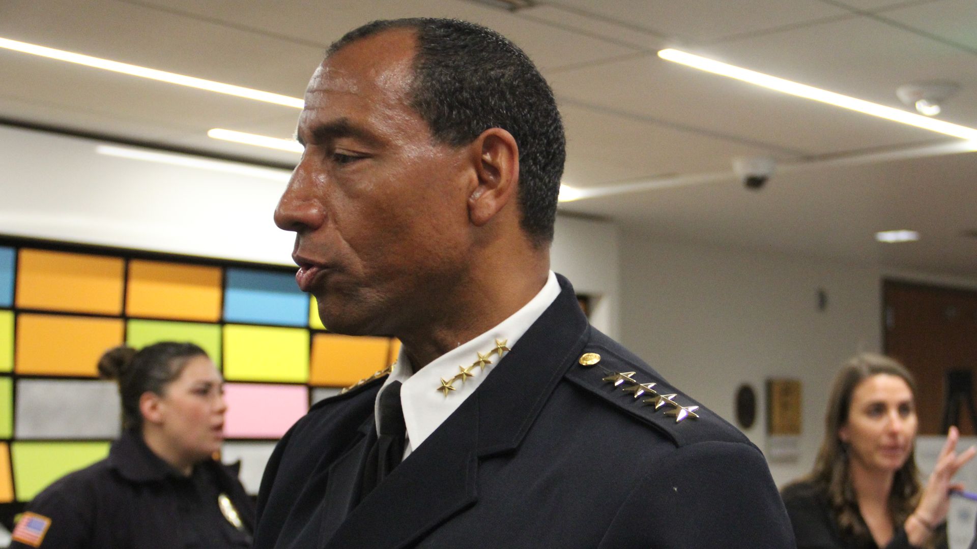 A man in a black police uniform speaks to someone.