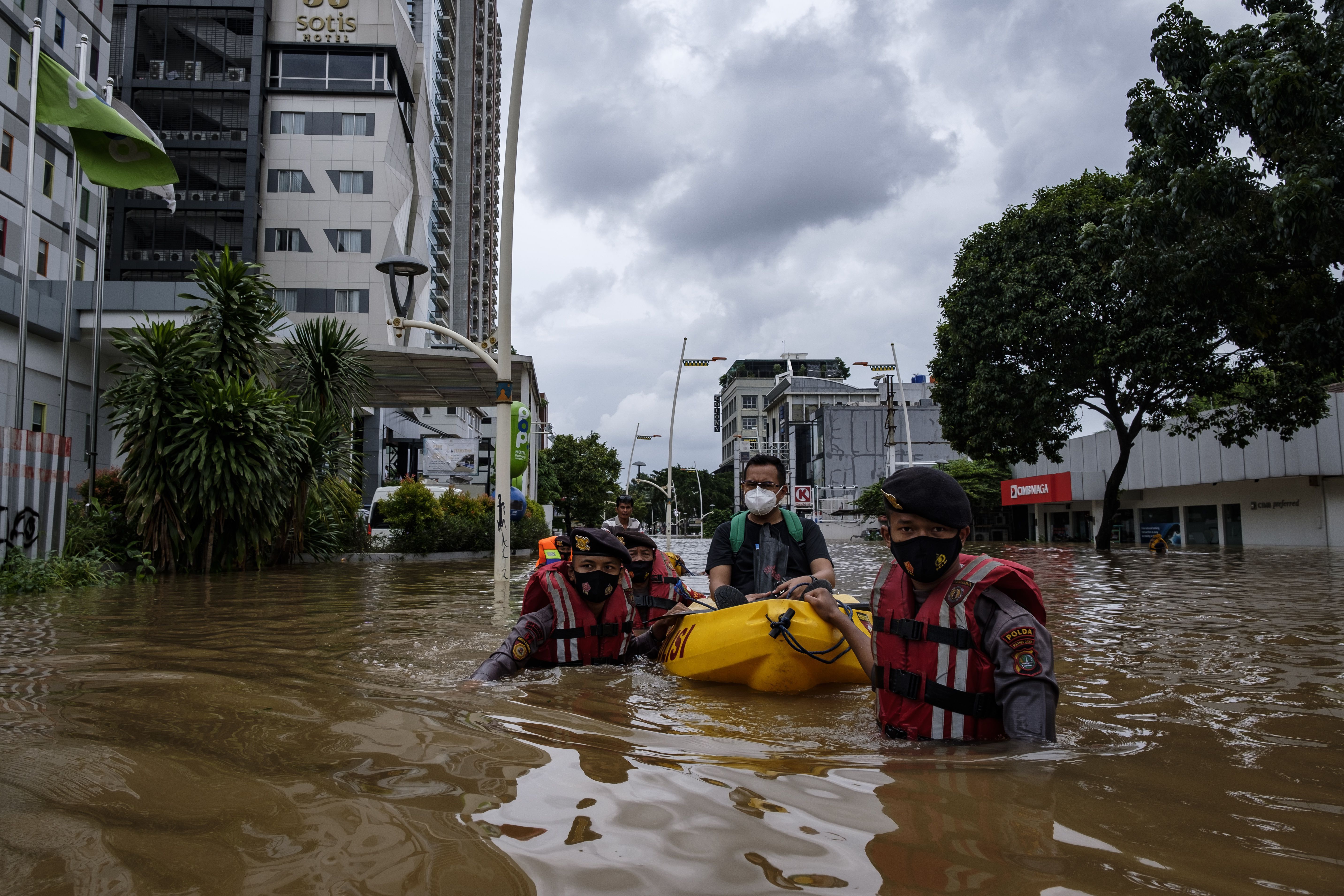 Policemen evacuate a man from a flooded business district on February 20, 2021 in Jakarta, Indonesia.