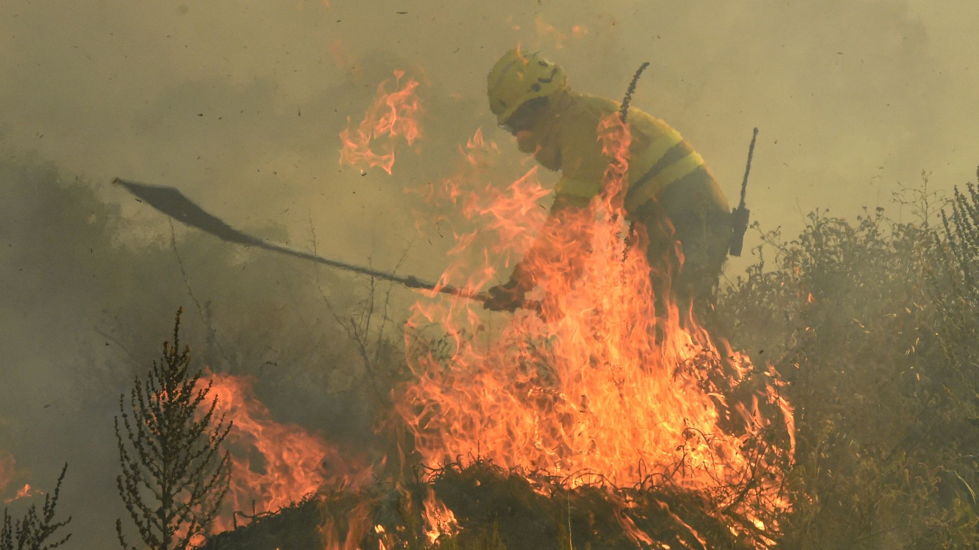 Firefighter uses a shovel to try to help mop up burning flames during a heat wave in Spain.