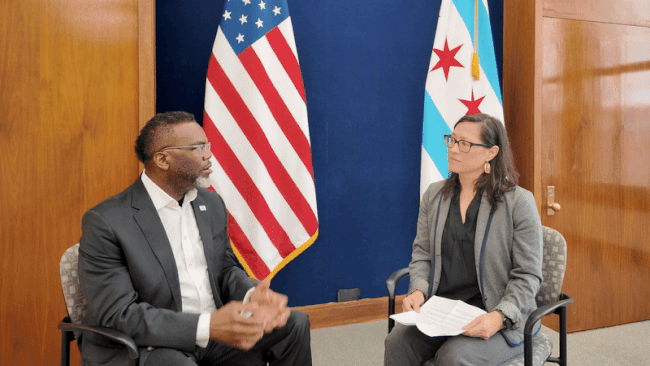 two people talking in front of a flag