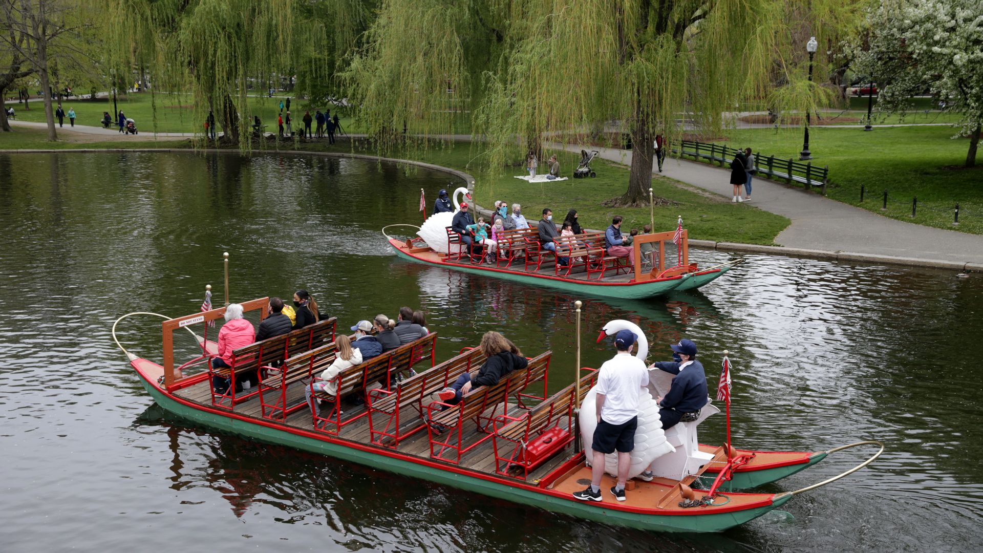 Two swan boats ride around the pond at The Public Garden in Boston. The boats typically need at least 10 people on board to operate.
