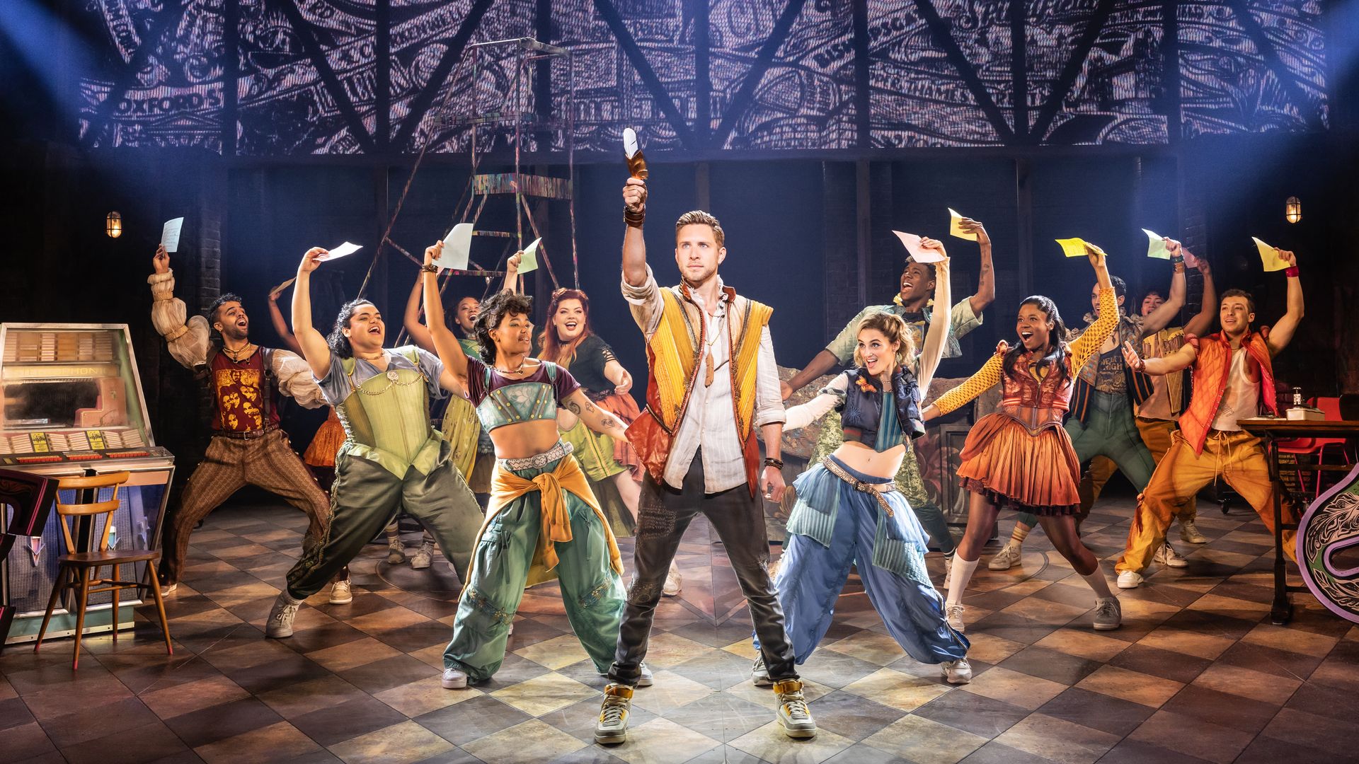 Cast of Broadway's & Juliet singing on stage, holding papers