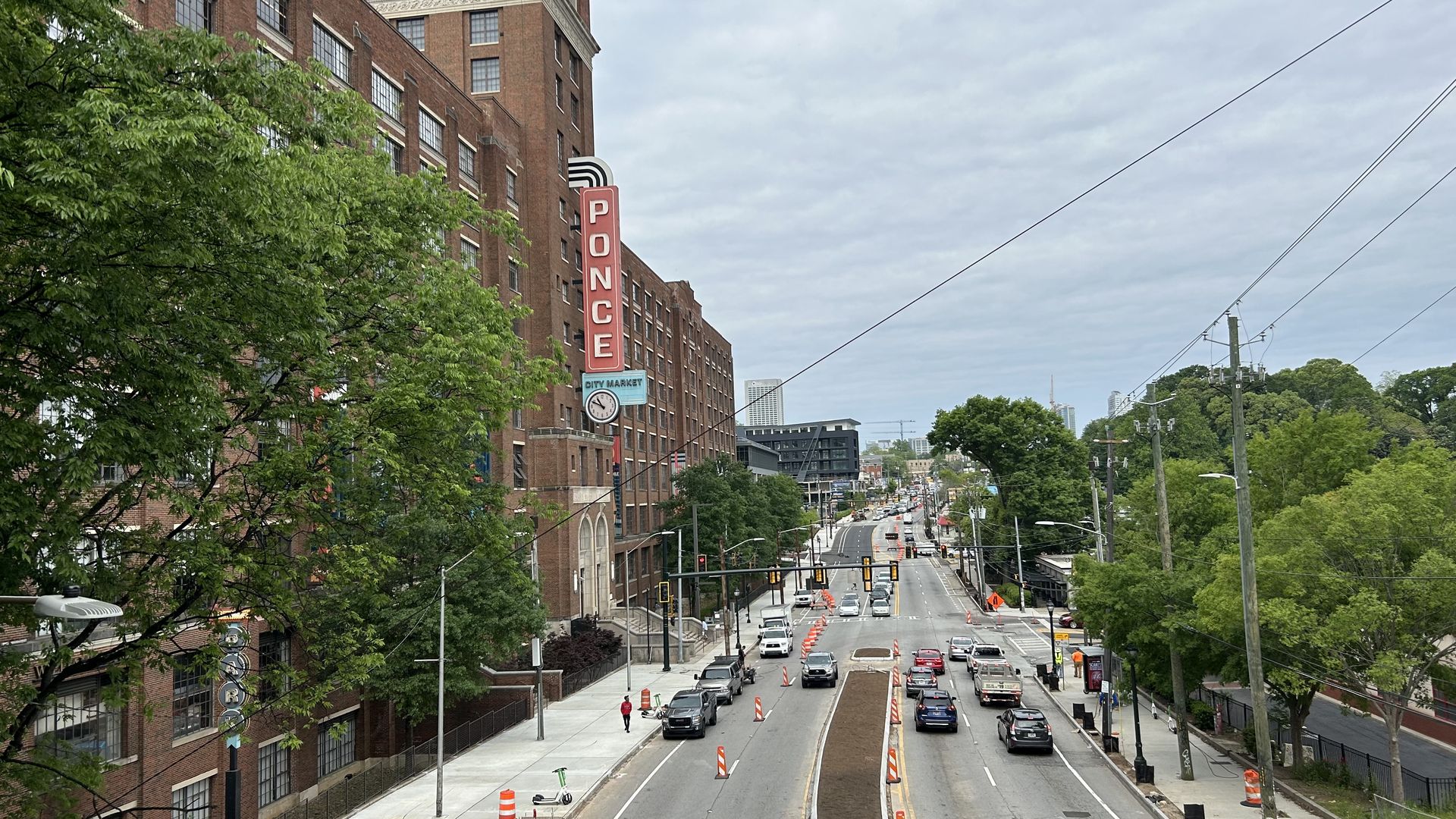 A photo of cars driving past a large brick mixed-use building with a vertical "PONCE" sign