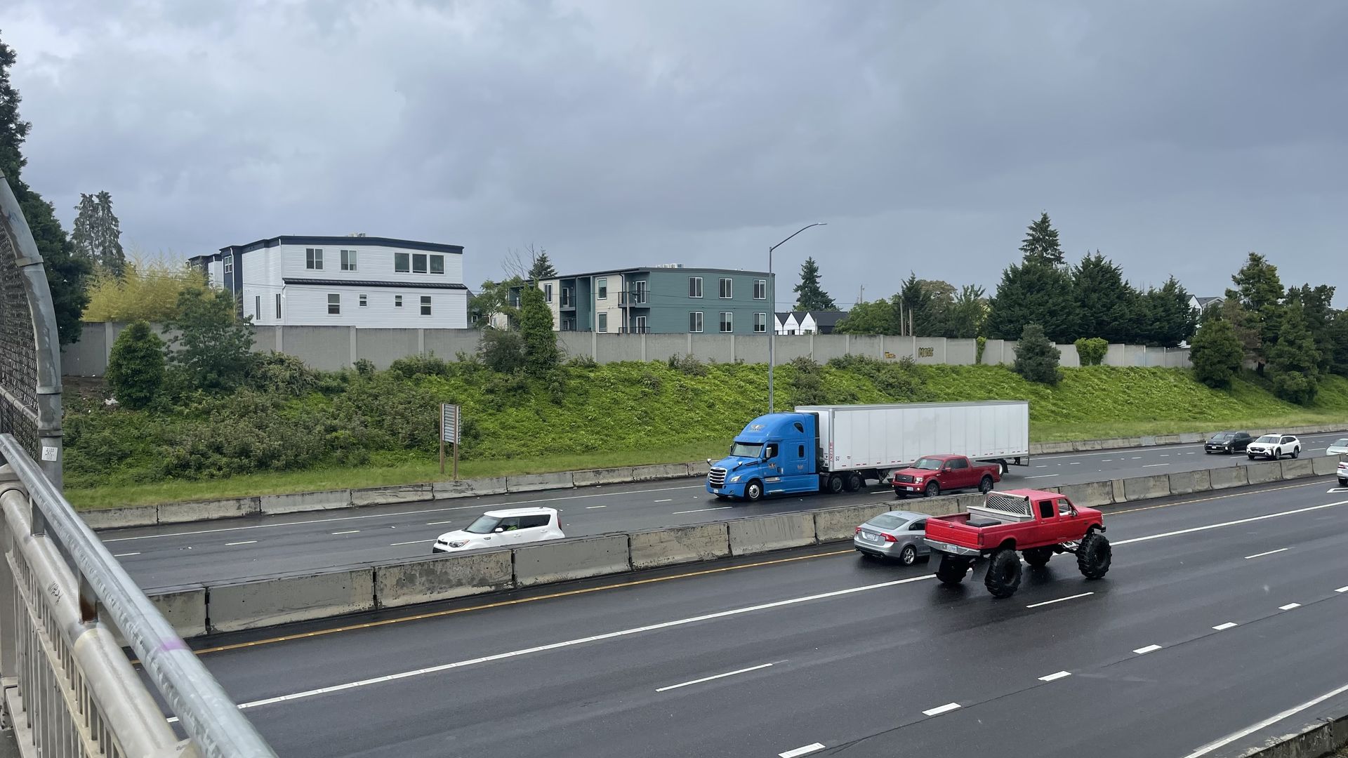 trucks and cars on a freeway in front of walls with no graffiti