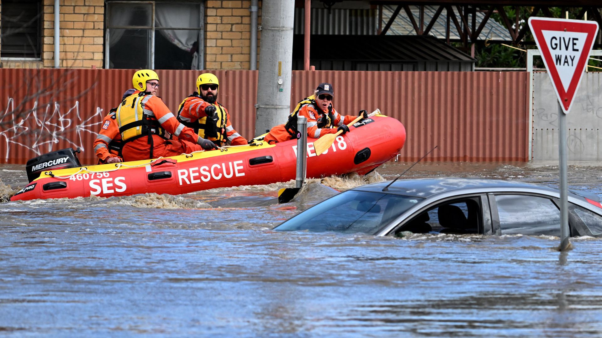 Rescuers pass a car inundated by floodwaters in Australia. 