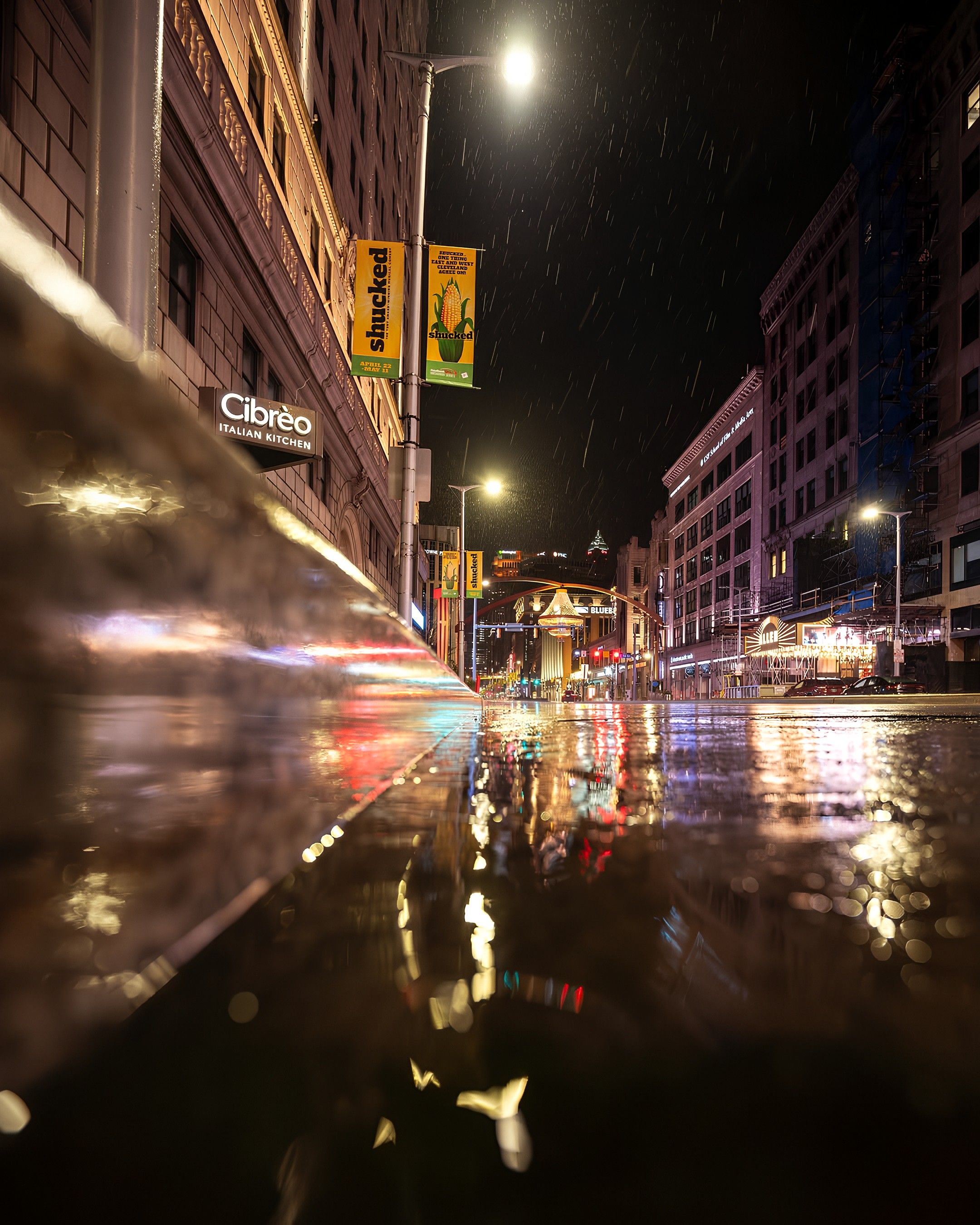 Photo of a street reflecting its buildings and lights on rain. 