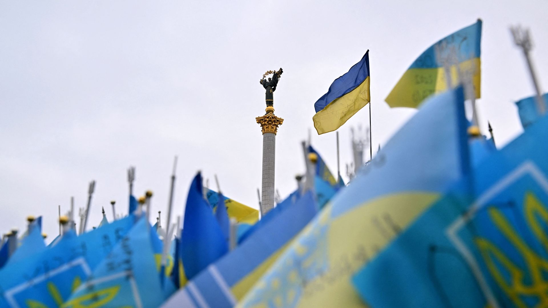 Photo of a monument with several Ukrainian flags flying in the foreground