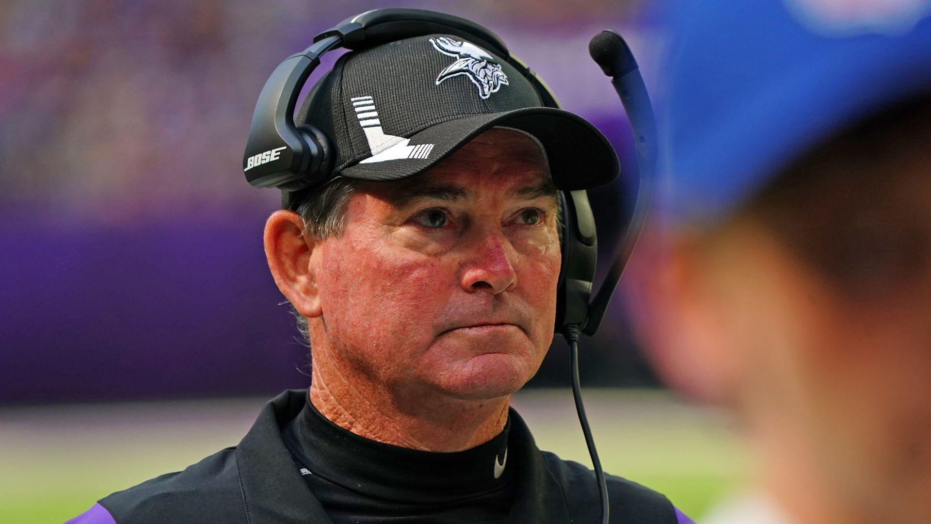 Mike Zimmer wears a black hat and headset 