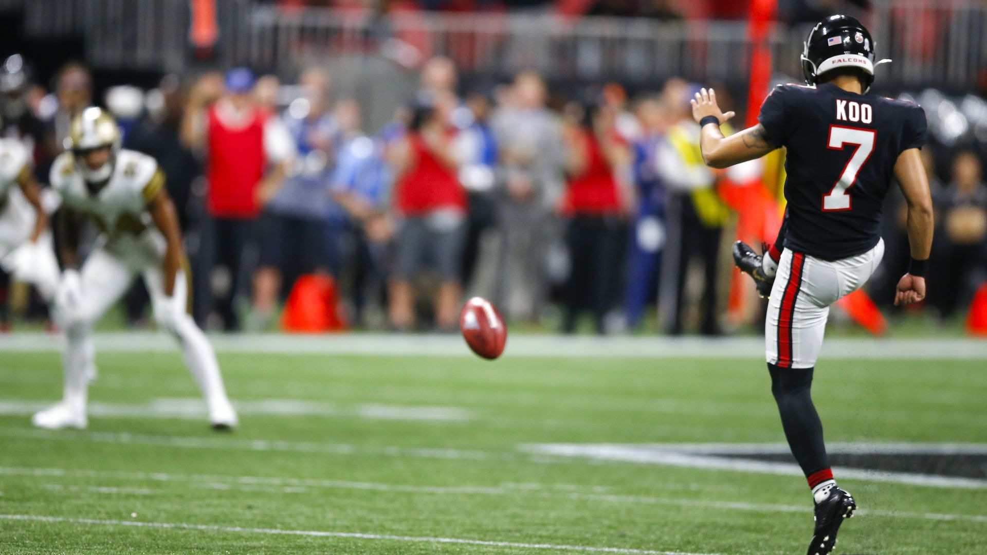 A football player kicking a football in the middle of a game