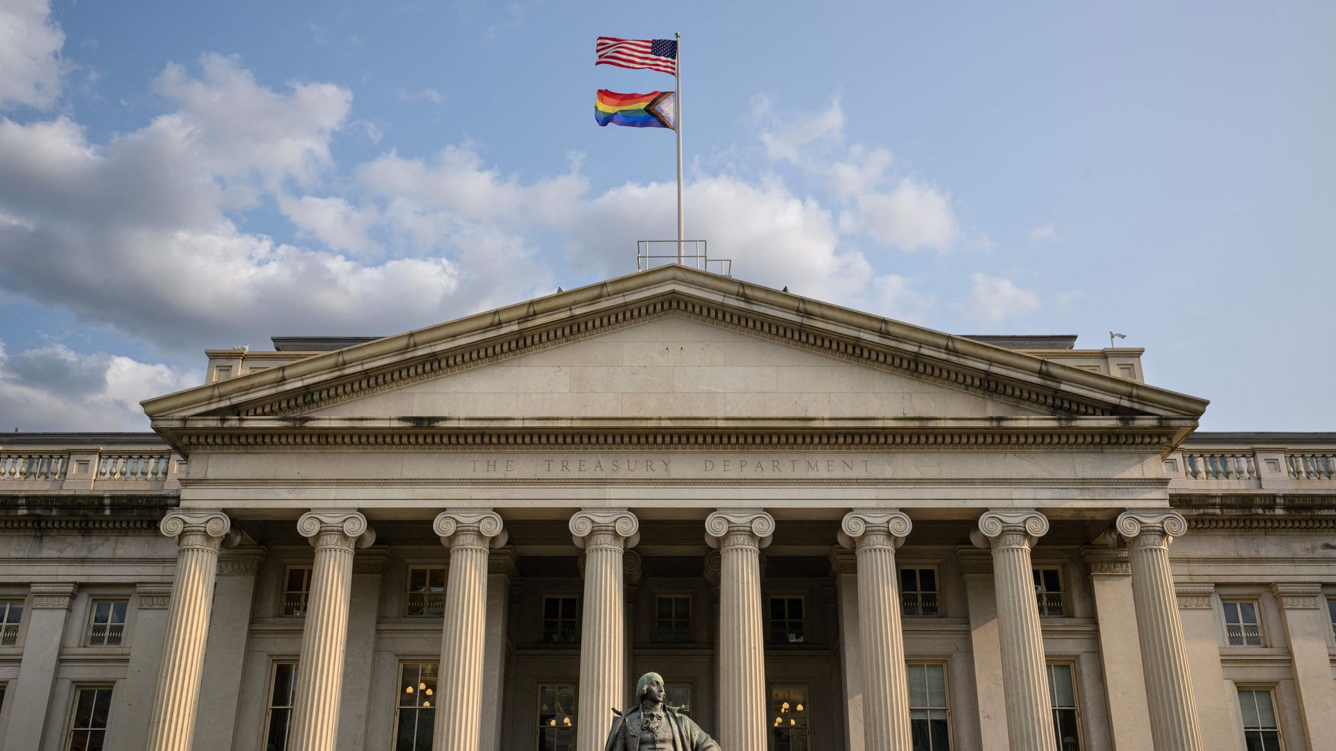 Two flags fly over a building with ornate columns