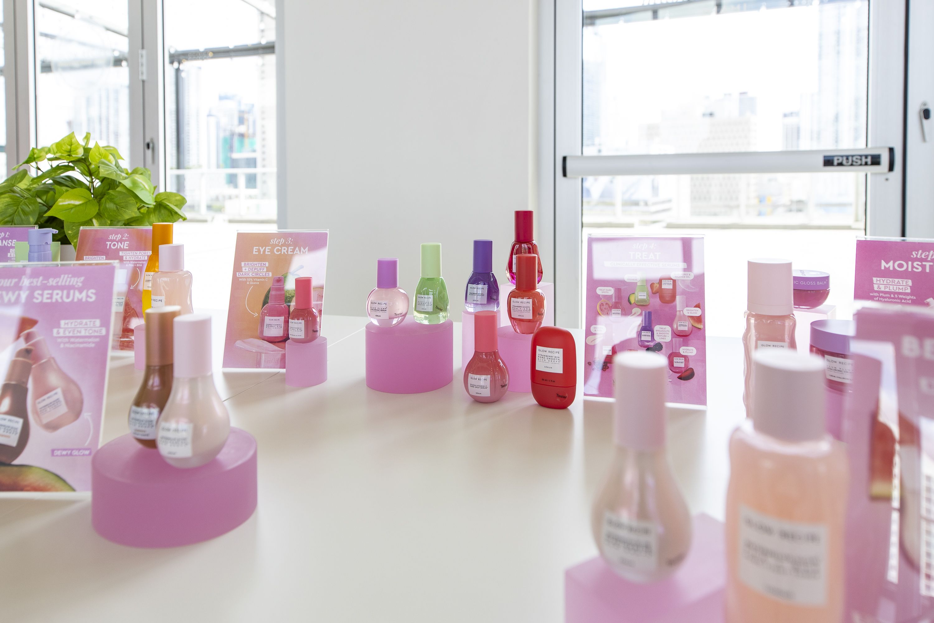 Small bottles in different colors sitting on top of pink round pedestals.