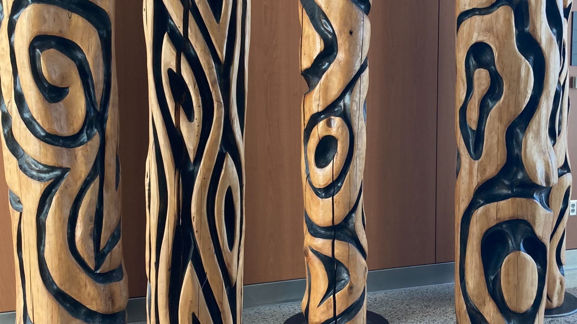 Four wooden columns with carved curvature details, inlaid in black, are shown.