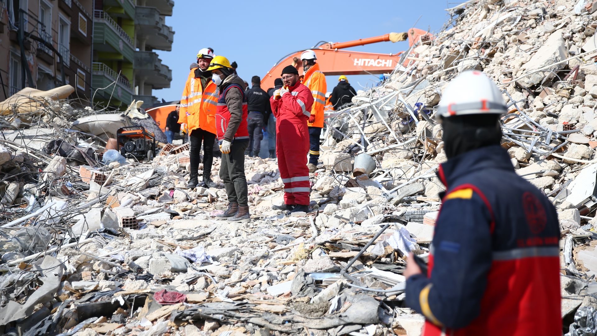 Photo of rescue workers standing on a pile of rubble