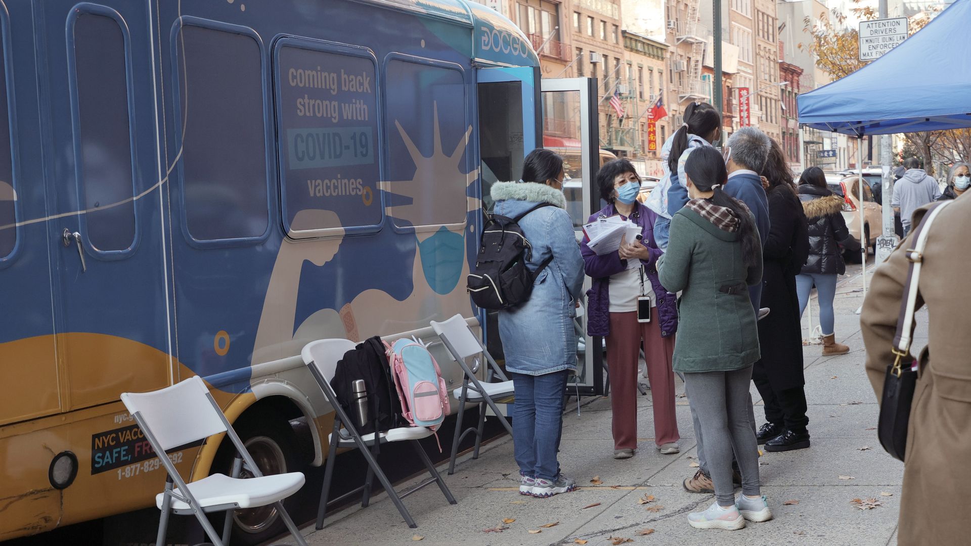 Principal Alice Hom (purple jacket) stands outside Yung Wing School P.S. 124 and a vax van.