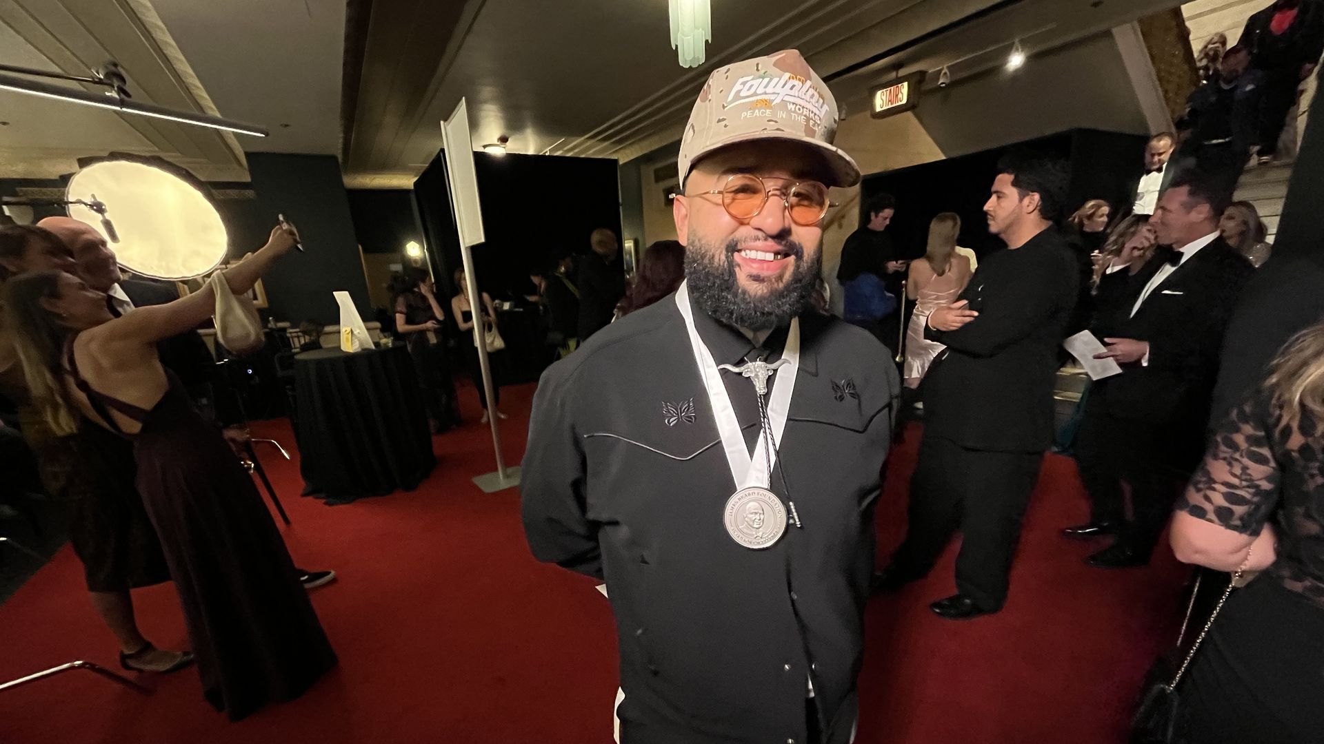 A man smiling and wearing a medallion.