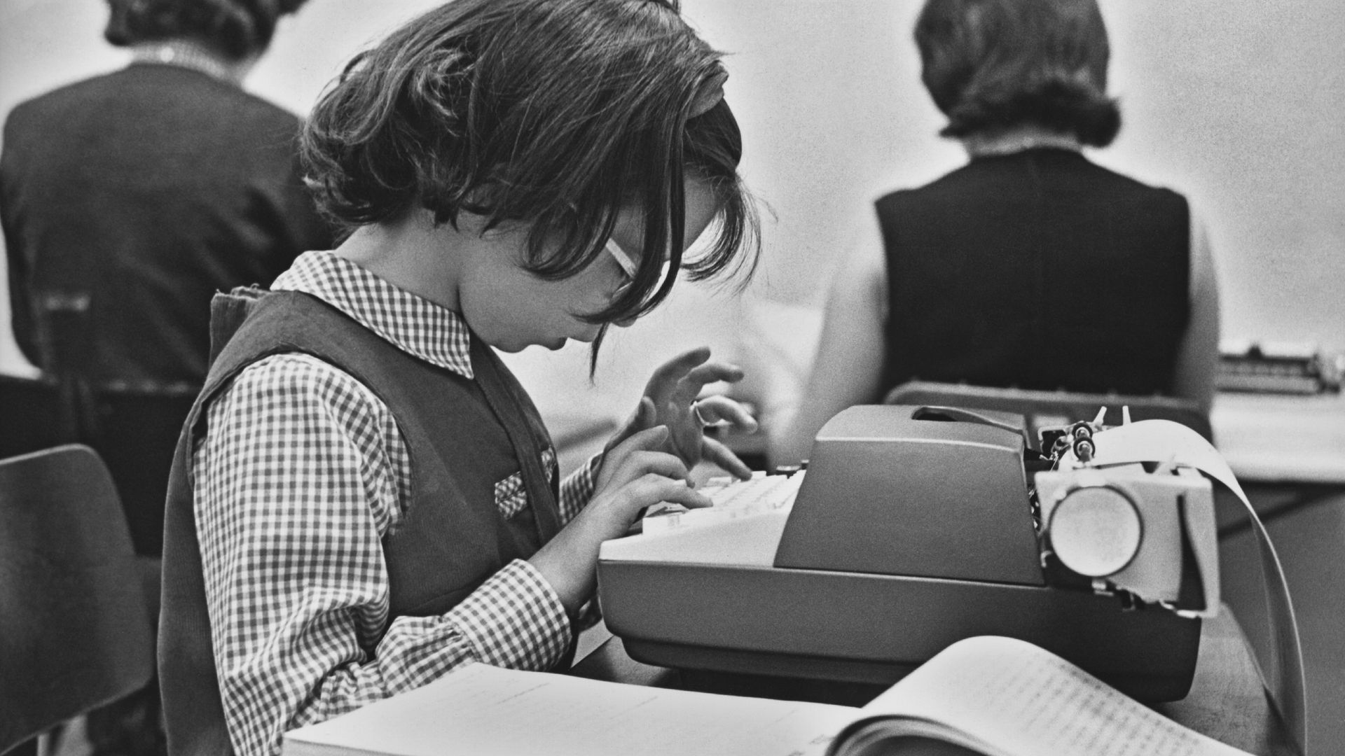 A young child learns to type on a typewriter. 