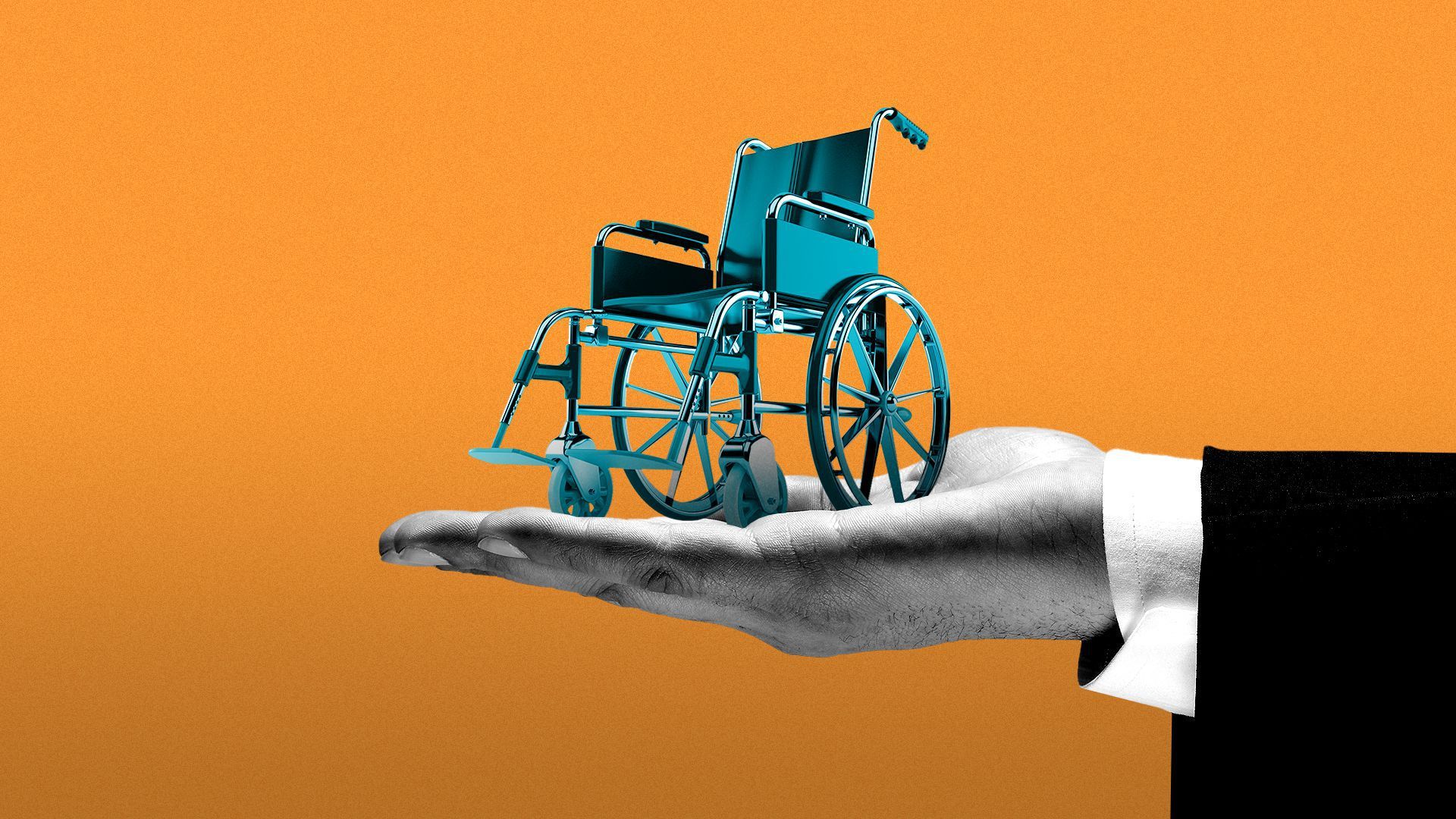 A wheelchair sits in the palm of a person's hand.