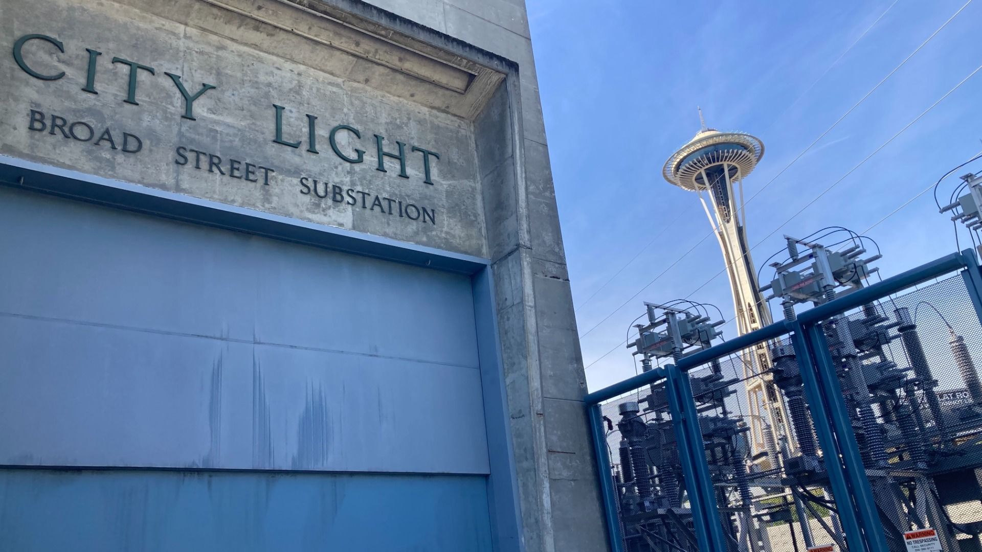 A concrete building with a garage-style door says "Seattle City Light Broad Street substation" with the Space Needle in the background to the right.