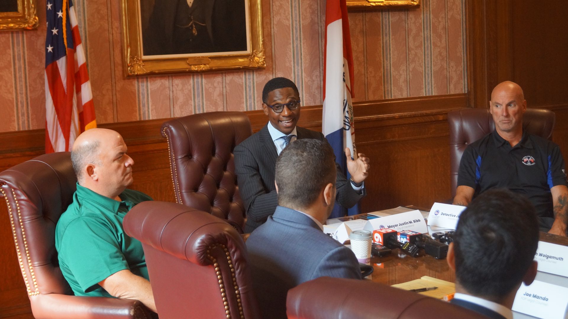 Mayor Justin Bibb at the head of the conference table in the Mayor's Red Room, flanked by police union leadership