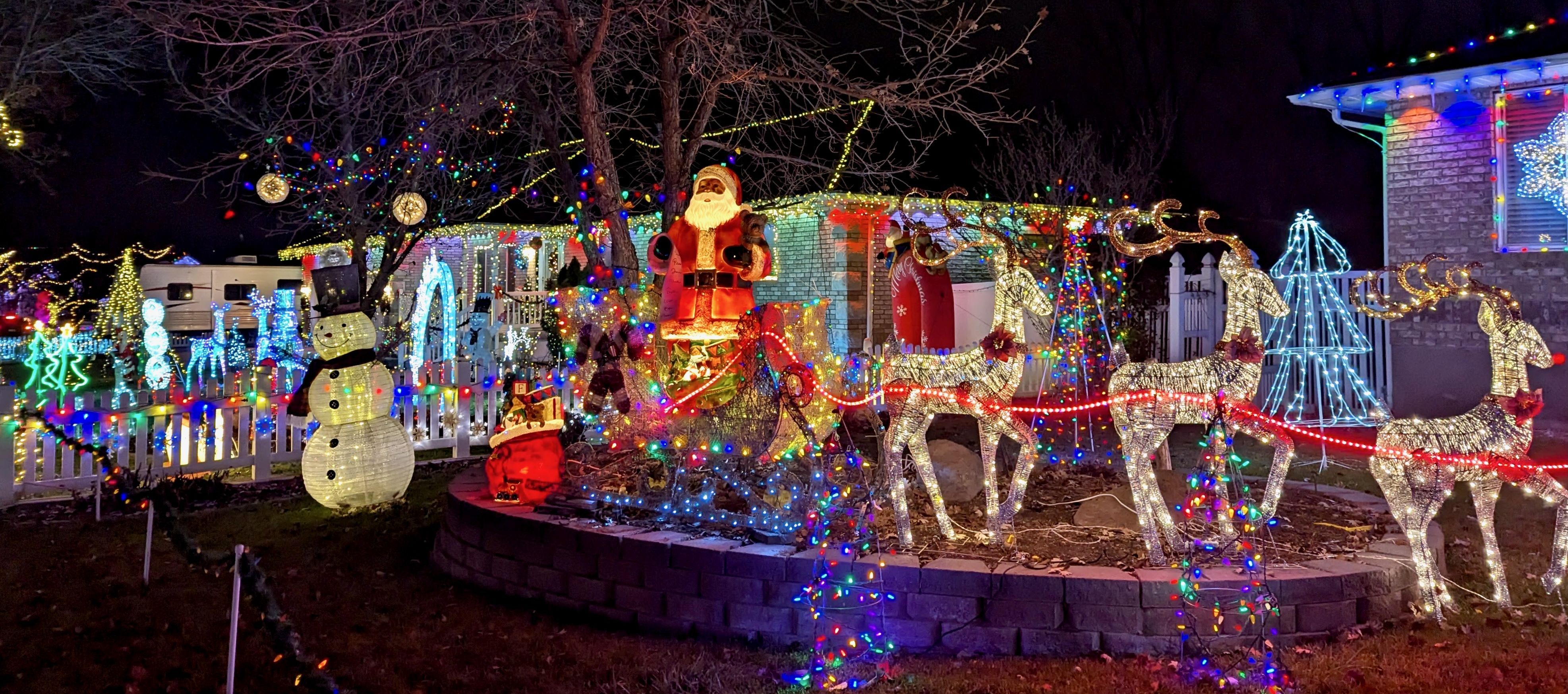 Multiple houses decorated with Christmas lights and large figurines and ornaments.