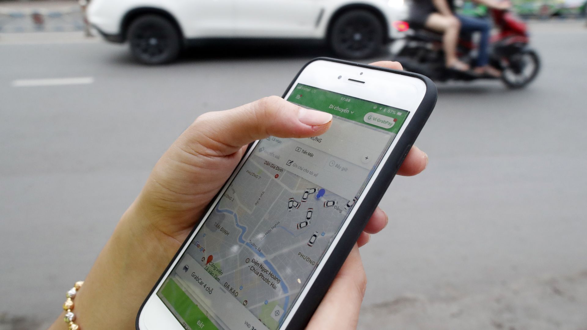 Photo of woman holding smartphone with Grab ride-hailing app.