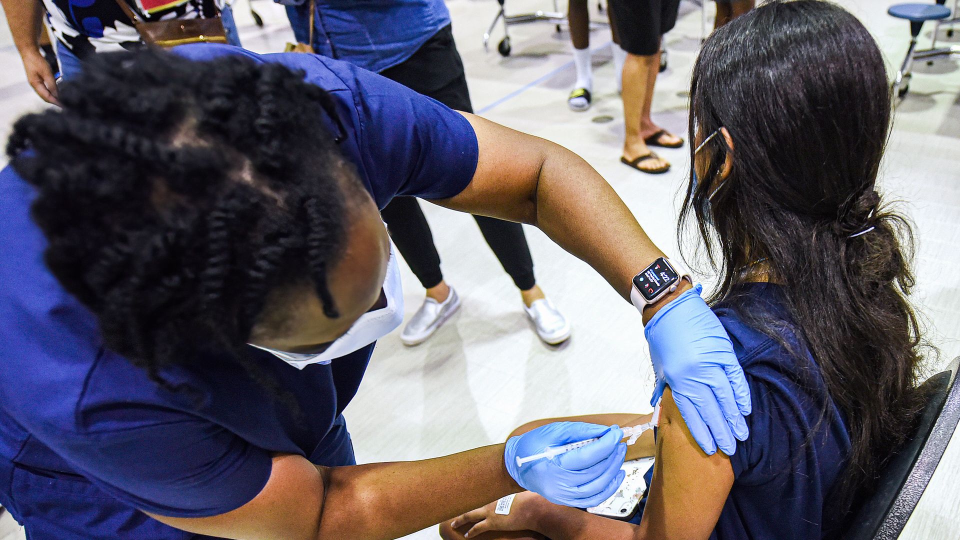 A nurse gives a girl a dose of the Pfizer vaccine at a COVID-19 vaccine clinic at Lyman High School in Longwood on the day before classes begin for the 2021-22 school year.